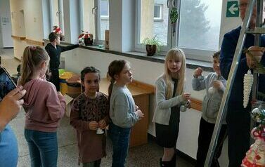 Uczniowie z Zespołu Szkolno - Przedszkolnego wieszający bombki na choince w Urzędzie Gminy Przeworno.