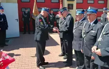 Na zdjęciu Komendant Gminny wręcza podziękowanie dla Strażak&oacute;w Ochotniczej Straży Pożarnej