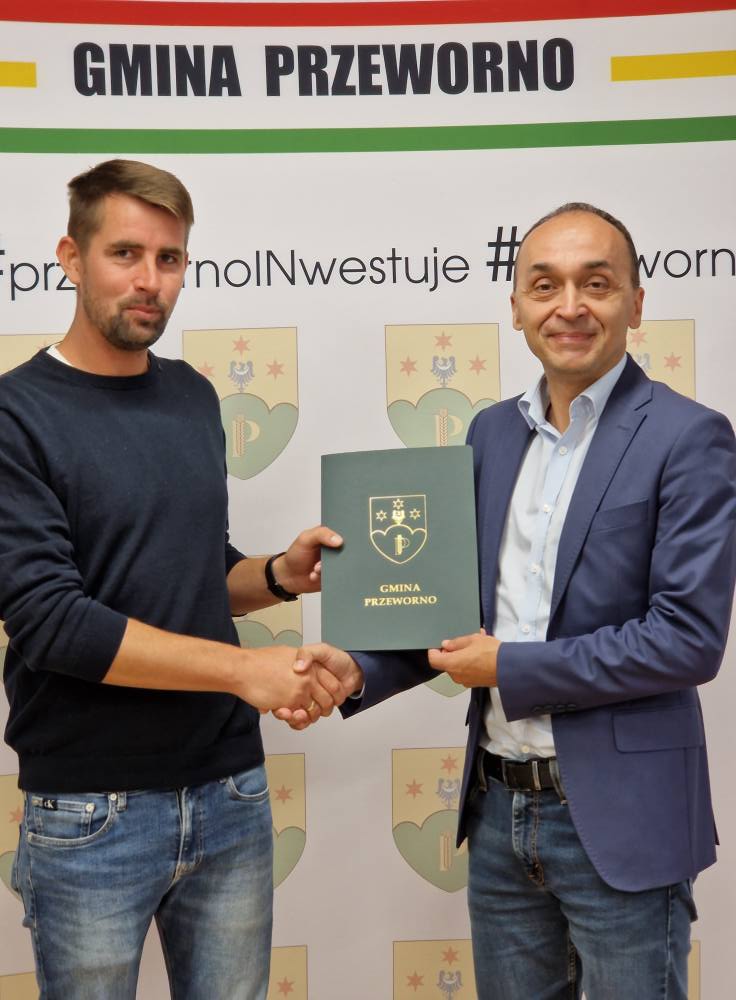 Na zdjęciu wykonawca inwestycji oraz Wójt Gminy Przeworno trzymający teczkę z podpisaną umową na realizację zadania. 