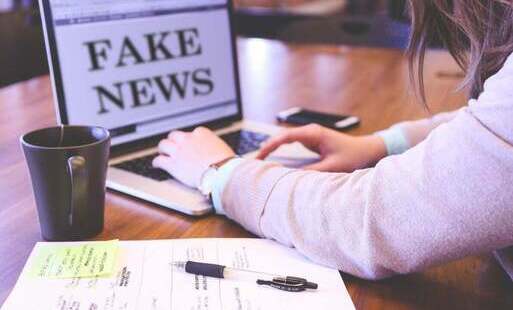 Obraz memyselfaneye z Pixabay_Osoba pracująca przy laptopie_Na monitorze komunikat fake news